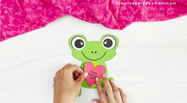 hands gluing heart to frog Valentine craft