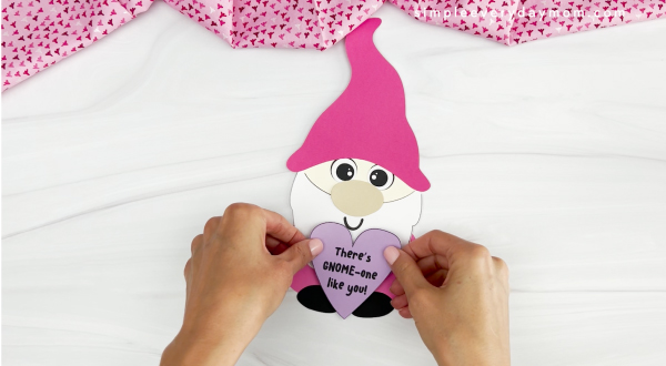 hands gluing love note onto body of gnome