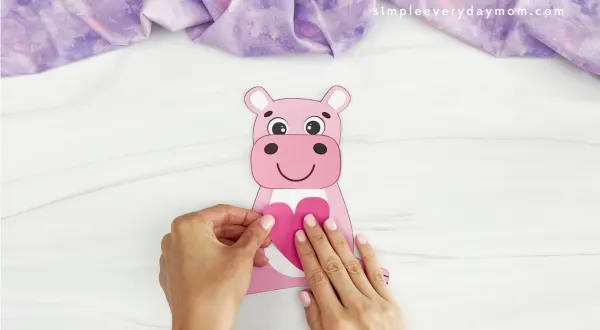 hands gluing heart to hippo Valentine craft