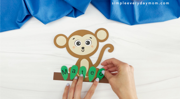 hands placing letters to name onto monkey name craft