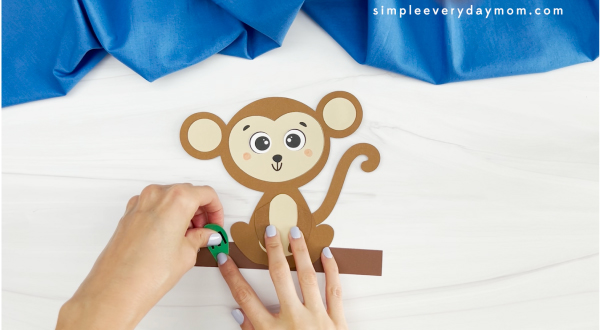 hands placing letter of name onto branch of monkey name craft
