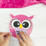 hands gluing wings onto body of Valentine owl craft