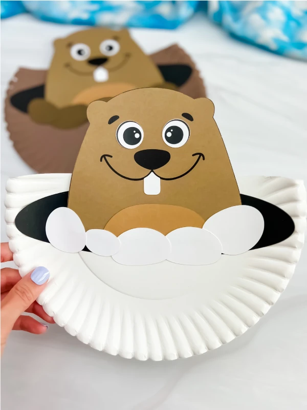 hand holding a finished example of groundhog paper plate craft