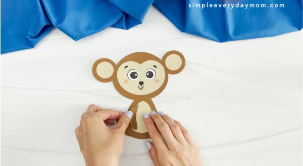 hands gluing arms onto body of monkey name craft