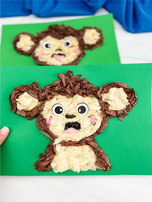 hand holding monkey tissue paper craft with another one in background