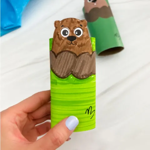 hand holding finished groundhog toilet paper roll craft colored with markers