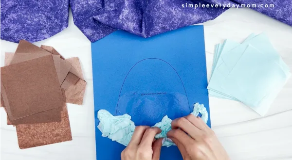 hands placing tissue paper onto printed template of walrus tissue paper craft