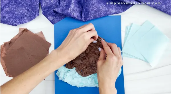 hands placing tissue paper onto walrus tissue paper craft