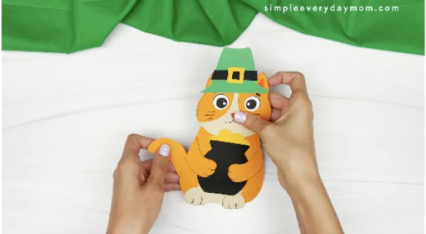 hands gluing tail to back of cat leprechaun craft