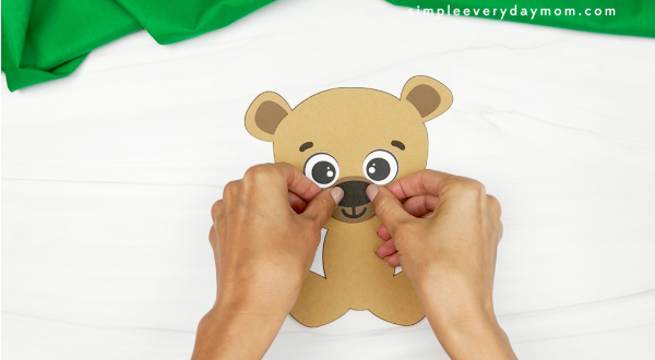 hands gluing nose to face of teddy bear