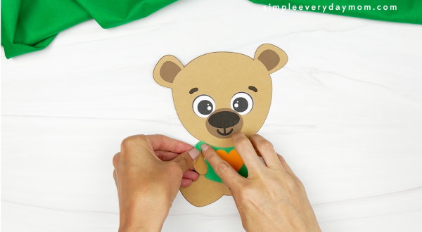hands gluing arms onto teddy bear