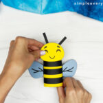 hands assembling bee face onto bee body