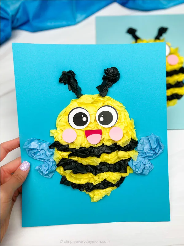 hand holding tissue paper bee craft with another example in background