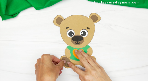 hands gluing legs onto teddy bear