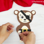 hands gluing arms onto monkey