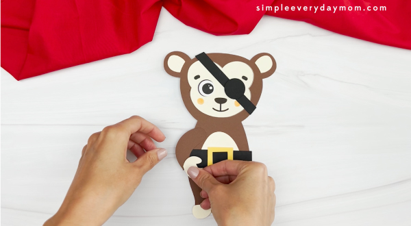 hands gluing arms onto monkey
