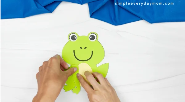 hands gluing arms onto frog name craft