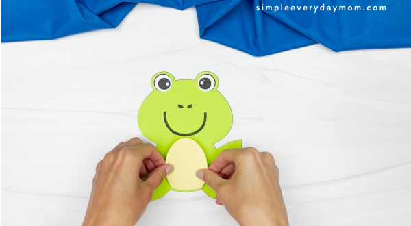 hands assembling parts of frog name craft