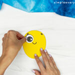 hand gluing eye onto face of bee