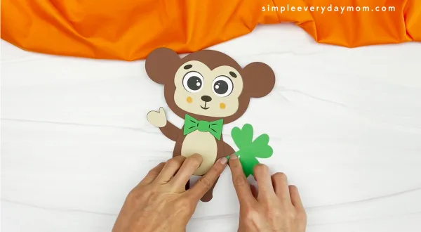 hands gluing clover onto monkey hand