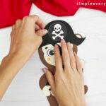 hand gluing pirate hat onto head