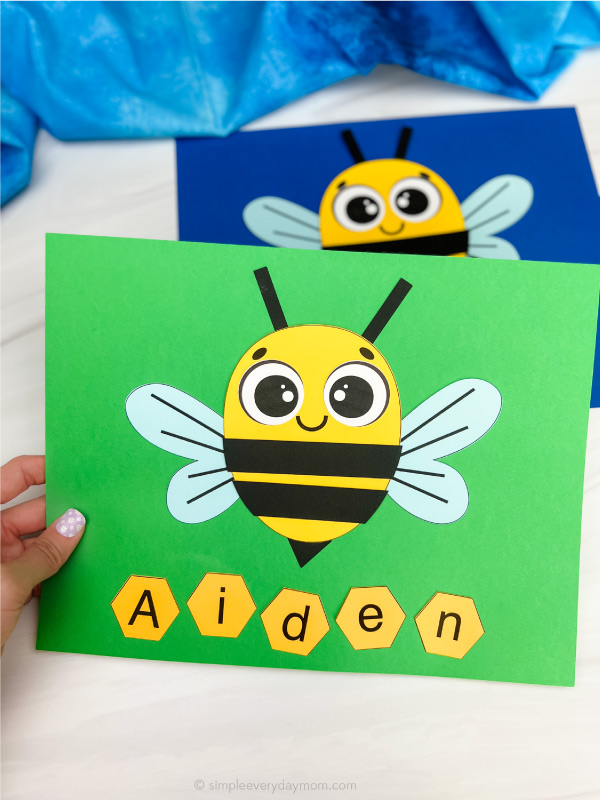 hand holding finished bee name craft in green with another example in background