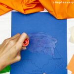 hands using glue stick to apply glue to the printed template
