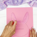 hands using glue stick to cover area where tissue paper will be