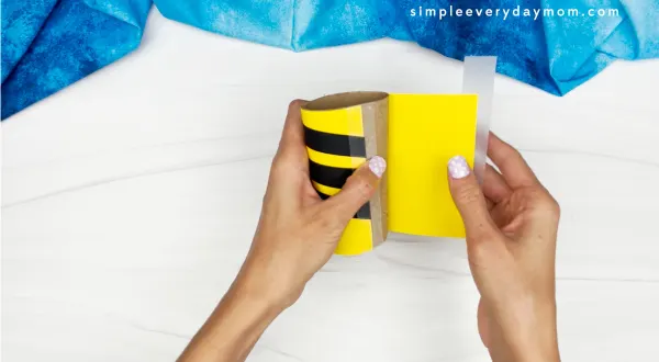 hands gluing bee body onto tp roll