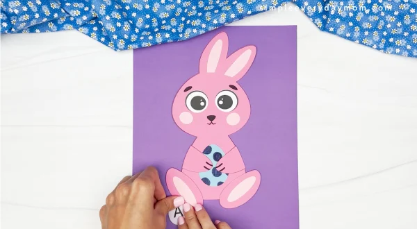 hands gluing letter A to sheet of paper with finished bunny