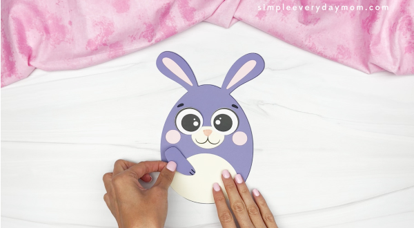 hands gluing arms onto Easter egg bunny