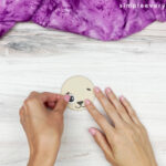 hands gluing eye onto sheep face