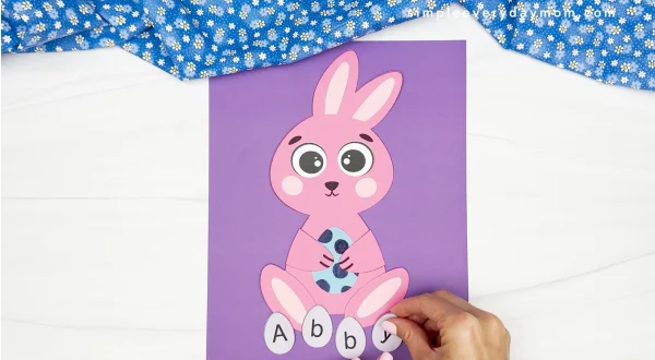 hands gluing the letter Y to finished bunny name craft
