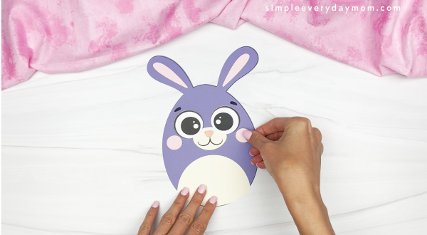 hands gluing cheeks onto Easter egg bunny