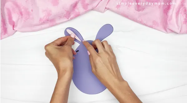 hands gluing parts of the ear onto Easter egg bunny
