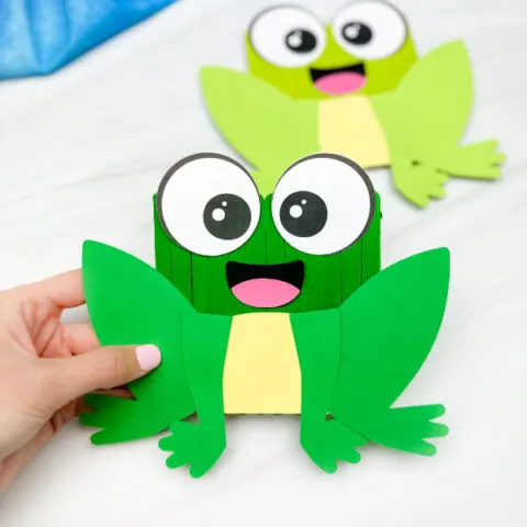 hand holding popsicle stick frog craft with another example in background