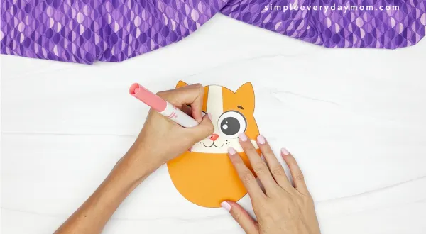 hands using marker to finish nose on Easter egg cat craft