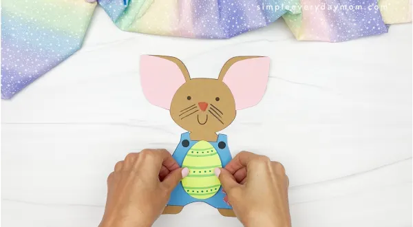 hands gluing decorated easter egg onto mouse
