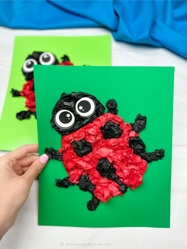 hand holding finished ladybug tissue paper craft with another in background