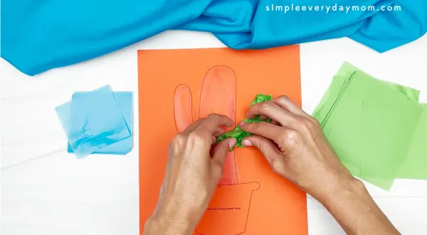 hands placing tissue paper onto glue