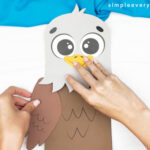 hands gluing feathered arms onto body