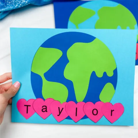 hand holding earth day name craft with another in background