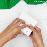 hands gluing sheep fur to the tp roll