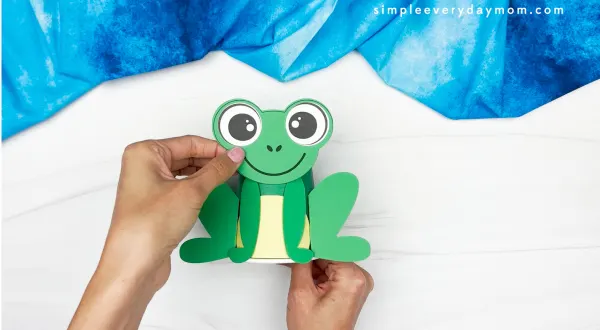 hands gluing frog head onto cup