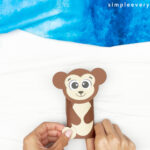 hands gluing feet to monkey
