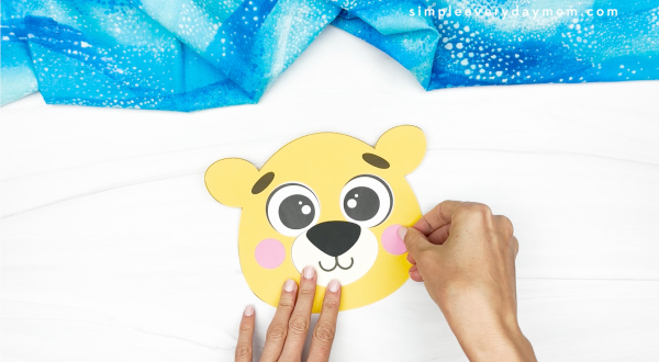 hands gluing lion face onto lion paper plate