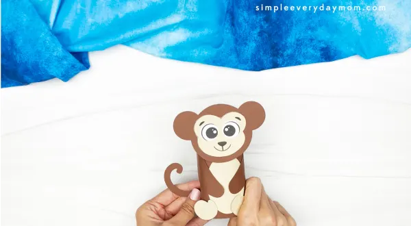 hands gluing tail to monkey body