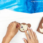 hands gluing eye to monkey face