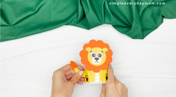 hands gluing lion tail to paper cup
