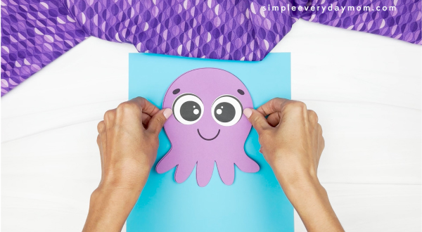 hands gluing octopus onto sheet of paper